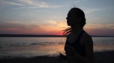 kamera gün batımında yavaş hareket sakin deniz tarafından kardiyo egzersiz zevk özel takım elbise çalışan kadın siluet ilerler