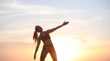 ihale ve esnek genç bayan parlak batan güneş ışığı yakın görünümü yavaş hareket karşı ayakta kasları uzanır