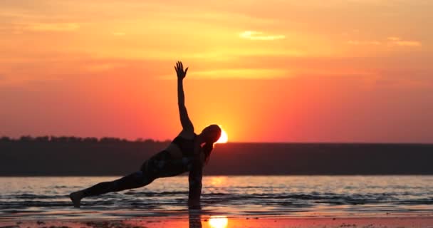 ポニーテールを持つ若い女性はヨガアダナを練習し 夕方の太陽に対して空に腕を上げる脚の筋肉を伸ばします — ストック動画