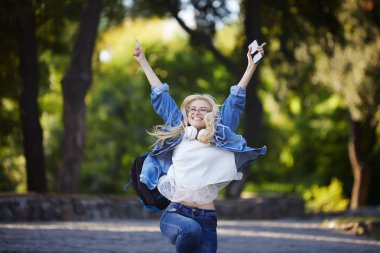 Genç heyecanlı kadın öğrencinin ön görünümü bir üniversite kampüsü veya sokakta bir cep telefonu satırında iyi haber alıyor. Kazanan kavramı