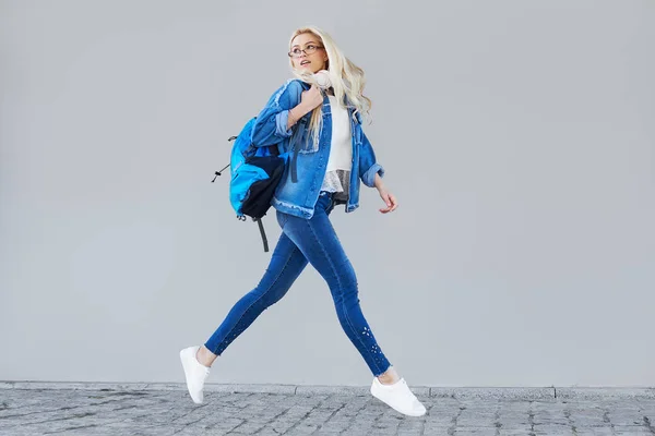 バッグと携帯電話で歩く幸せな若い女性の全身肖像画 灰色の背景の上に空中ジャンプ陽気な学生 — ストック写真