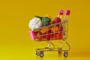 Taze sebze ve meyveler ile bakkal alışveriş sepeti. Sarı arka planda izole edilmiştir. Ücretsiz GMO. Suni plastik ürünler
