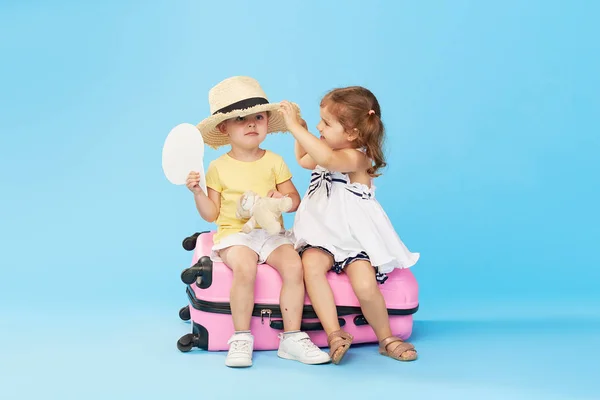 휴가를 다채로운 분홍색 가방에 앉아있는 행복한 아이들 여행자 소녀와 여동생과 — 스톡 사진