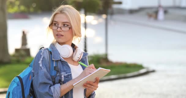 Όμορφη κυρία με μπλε ντένιμ μπουφάν κοιτάζει γύρω και γράφει — Αρχείο Βίντεο