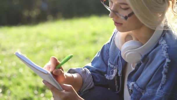 Chica inspirada en aderezo denim escribe en cuaderno de papel — Vídeo de stock