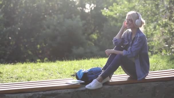 Blond girl in casual dressing dances sitting on bench — Stock Video
