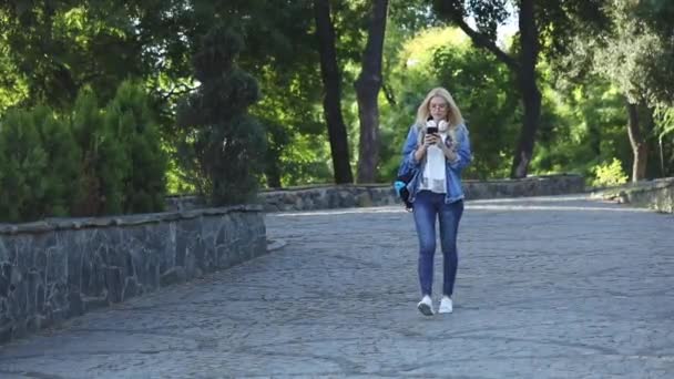 Молодая женщина пошутила, глядя на смартфон в парке — стоковое видео