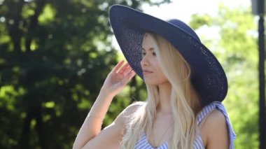 geniş saplı şapkalı çekici Bayan gülümsüyor ve uzakta yürüyor