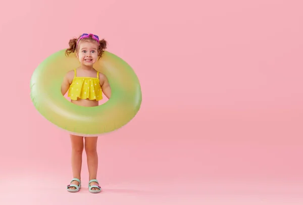ピンクの背景に孤立した楽しみを持つネオン膨脹可能なゴムサークルを持つ幸せな小さな女の子の肖像画 右側のテキスト用のスペース — ストック写真