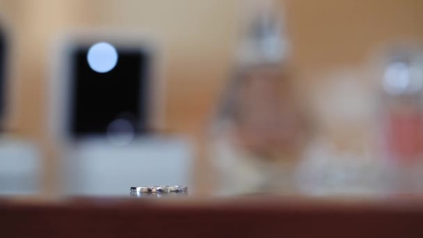 Gold wedding ring rolls to pair on red table slow motion — Stock Video