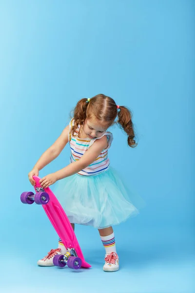 Cool Pequeña Niña Ropa Brillante Sostiene Monopatín Mirando Cámara Aislada —  Fotos de Stock