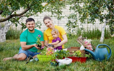 Mutlu aile birlikte bahçe ve doğa bakımı. Bitki lahanası ve toprak döllemek. Kailyard renkli parlak t-shirt Anne, baba ve küçük çocuk