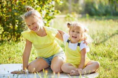 güneşli bir günde bahçede oynayan iki kız kardeş