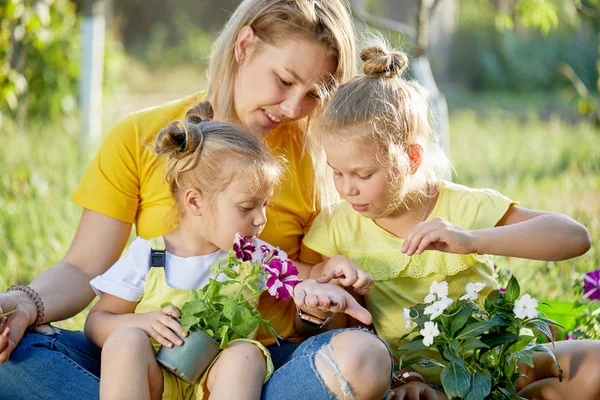 Little children in yellow playing with mom in garden on sunny day