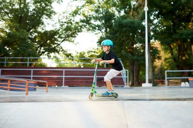 Scooter'lı ve koruyucu kasklı bir çocuk paten parkında inanılmaz gösteriler yapıyor. Aşırı atlayış. Sağlıklı bir yaşam tarzı ve spor eğlence kavramı