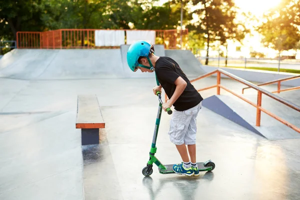 Scooter'lı ve koruyucu kasklı bir çocuk paten parkında inanılmaz gösteriler yapıyor. Aşırı atlayış. Sağlıklı bir yaşam tarzı ve spor eğlence kavramı