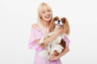 Spaniel köpek kucaklayan gülümseyen genç sarışın kadın Closeup portre. sahibi ve evcil hayvan ilişkileri kavramı. Veteriner. Beyaz arka planda yalıtılmış ön görünüm.