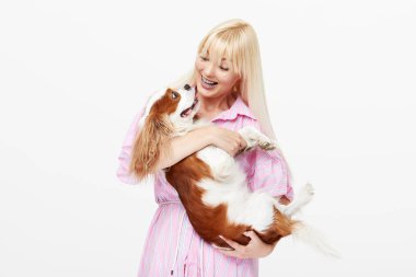 Spaniel köpek kucaklayan gülümseyen genç sarışın kadın Closeup portre. sahibi ve evcil hayvan ilişkileri kavramı. Veteriner. Beyaz arka planda yalıtılmış ön görünüm.