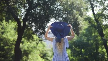 genç güzel sarışın kadın şapka koyar ve gülümseyerek yürüyor