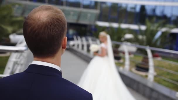 Αρραβωνιαστικός κοιτάζει τη νύφη σε μακρύ φόρεμα περπάτημα στη γέφυρα — Αρχείο Βίντεο