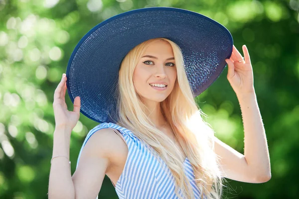 Wow effect. Fashionably dressed woman in vacation. Wearing stylish blue dress, straw hat and bracelet. Straight long blond hair. Summer Sale concept