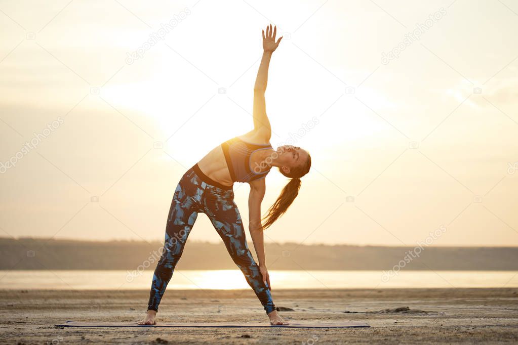 Yoga and fitness. Young woman practicing morning meditation in nature at the beach