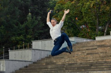 Deli genç işadamı çantaile sokakta dans ediyor. Zaferi kutluyoruz. İş hayatında esneklik ve zarafet