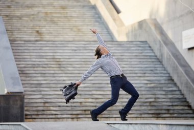 Deli genç işadamı çantaile sokakta dans ediyor. Zaferi kutluyoruz. İş hayatında esneklik ve zarafet