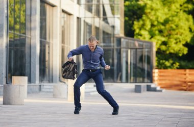 Deli genç işadamı çantaile sokakta dans ediyor. Zaferi kutluyoruz. İş hayatında esneklik ve zarafet