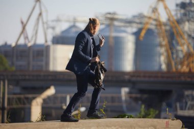 Dans eden işadamı büyük bir fabrikanın arka planında duruyor ve telefonda konuşuyor. İyi haber aldı.