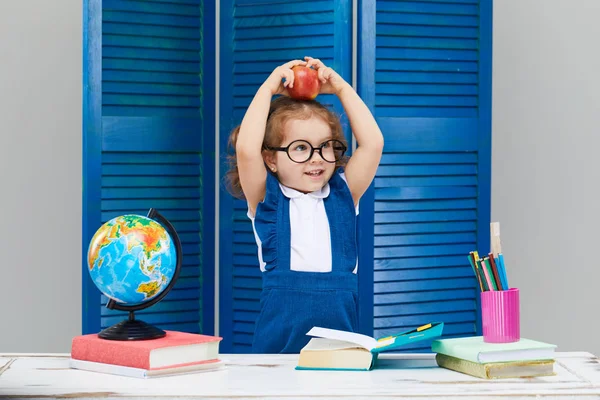 スマート幼児の子供 学校に戻って 幸せな時間 メガネをかけたかわいい勤勉な子供が屋内の机に座っている 子供は青い壁の背景にクラスで学んでいます 本を読んでいる少女 — ストック写真