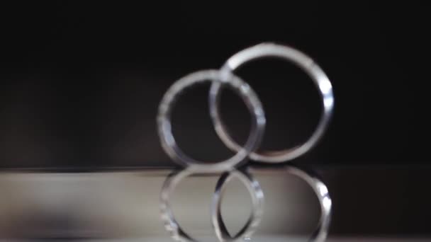 Elegantes anillos de boda de metal blanco sobre fondo negro — Vídeos de Stock