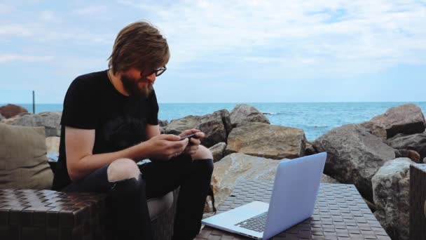 Man spelar på telefon sitter på modern laptop av Blue Sea — Stockvideo