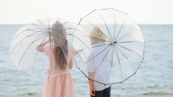 Fiú és lány átlátszó napernyőkkel a tengeren nyáron — Stock videók