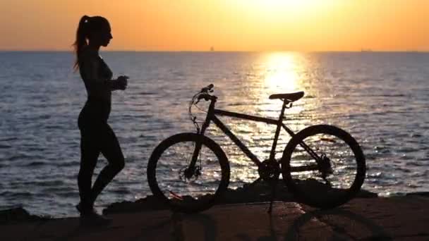 Sportieve dame silhouet strekt de handen tegen zonsondergang — Stockvideo