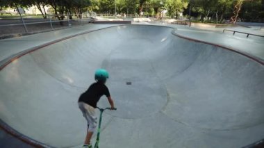 t-shirt ve şort çocuk paten parkı boyunca scooter sürmek