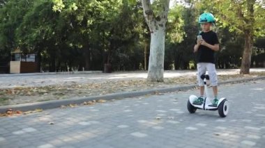 çocuk kendini dengeleyen segway sürmek ve akıllı telefon üzerinde çalış