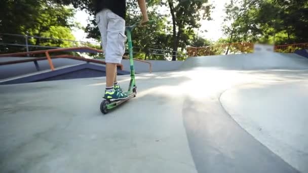 Kind fährt grünen Roller am modernen Skatepark-Pool entlang — Stockvideo