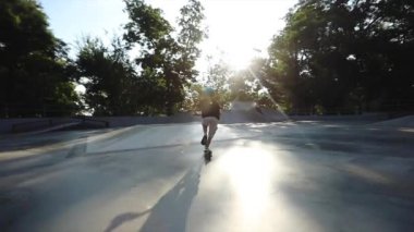 çocuk güneşli bir günde gri paten parkı boyunca scooter sürmek