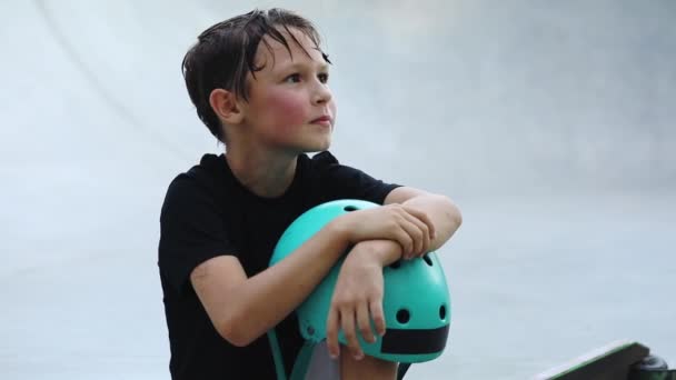 Garçon avec les cheveux mouillés après l'entraînement se trouve tenant casque sur le genou — Video