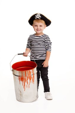 Cadılar Bayramı'nda mutlu çocuk. Beyaz arka plan üzerinde turuncu boya büyük bir kova ile ayakta korsanların karnaval kostümleri Komik küçük çocuk. Hediye ver yoksa karışmam