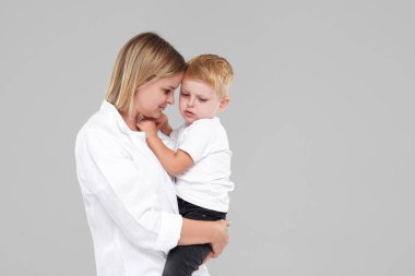 Genç anne ağlayan çocuğunu kucağına tutuyordu. Oğlu hasta ve kötü hissediyor, kadın üzgün bebek için üzgün