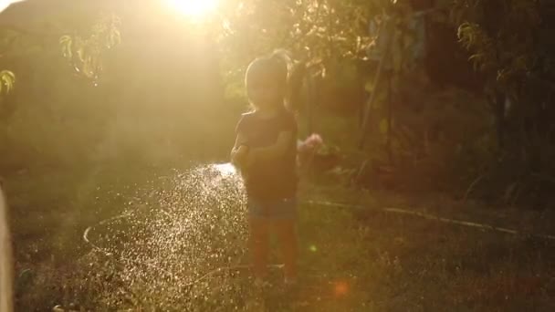Küçük kız sulu çim avlusunda yavaş hareket silueti — Stok video