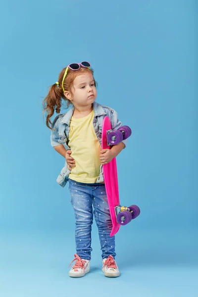 Cool Niña Pequeña Ropa Mezclilla Sostiene Monopatín Divertido Mirando Cámara —  Fotos de Stock