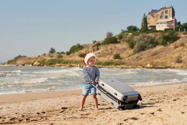 Małe Dziecko Santa Hat Rolkach Walizkę Tropikalnej Plaży Ferie Zimowe — Zdjęcie stockowe