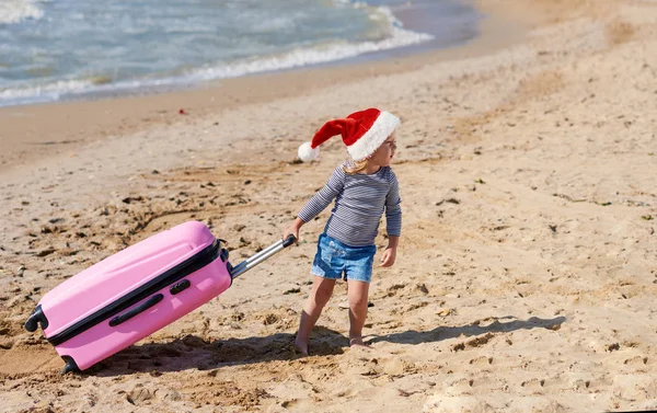 Małe Dziecko Santa Hat Rolkach Walizkę Tropikalnej Plaży Ferie Zimowe — Zdjęcie stockowe