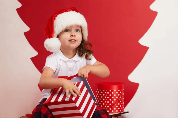 크리스마스와 홀리데이 귀여운 소녀는 실내크리스마스 트리를 장식하고 있습니다 빨간색 배경에 — 스톡 사진