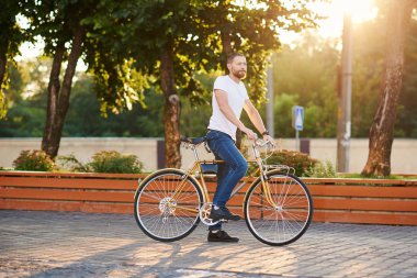 Gündelik kıyafetler giyen kırmızı sakallı adam sabah şehirde yolda bisiklete biner. Sağlıklı yaşam tarzı kavramı