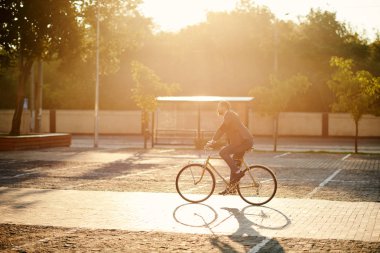 İş elbisesi içinde sakallı Işadamı gün batımında sabah kentsel sokakta çalışmak için retro bisiklet sürme