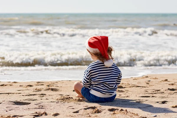 Mała Dziewczynka Santa Czerwony Kapelusz Działa Zabawy Tropikalnej Plaży Świąteczna — Zdjęcie stockowe